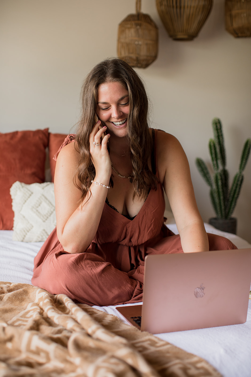 Heather Flynn smiling warmly on a video call from a cozy, plant-filled bedroom